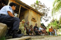 Fijian Participating Police Force advisor Lait Buakula and Warrant Officer Class Two Graham Bell listens in as locals sing for them in a village on the outskirts of Honiara.