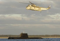 HMAS Manoora's SK50 Sea King helicopter flies over Collins Class submarine, HMAS Collins.