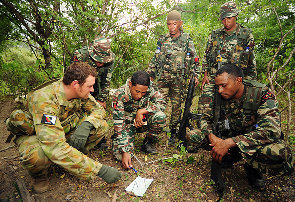 Captain Paul Sanderson with the Defence Co-operation Program (DCP) checks the navigation on a map with an East Timor Defence Force (F-FDTL) section from the Ready Company Group.
