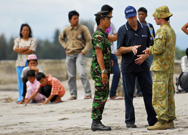 AusAID's Sam Zappia talks with Flying Officer Mick McGirr and an Indonesian military official on the beach of Pariaman.