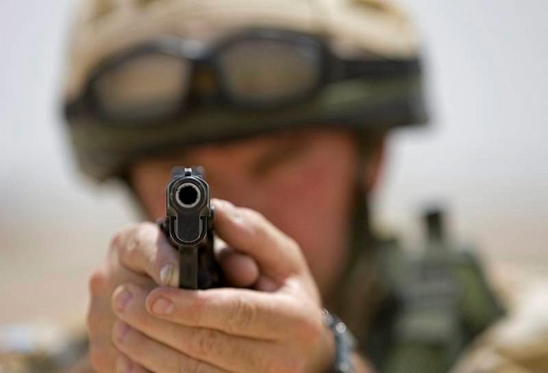 A British soldier aims a Browning 9mm pistol on a shooting range at Basra, Iraq