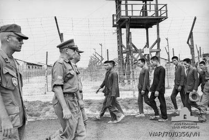 Bien Hoa, South Vietnam. June 1970. The Chief of Staff of the Headquarters Australian Force Vietnam, Colonel (Col) J. Whitelaw, passes a group of prisoners of war (POWs) during his inspection of the III Corps POW cage. Col Whitelaw presented a small library to the camp. He was accompanied on his inspection by the Vietnamese commandant, Major Sanh Qui.