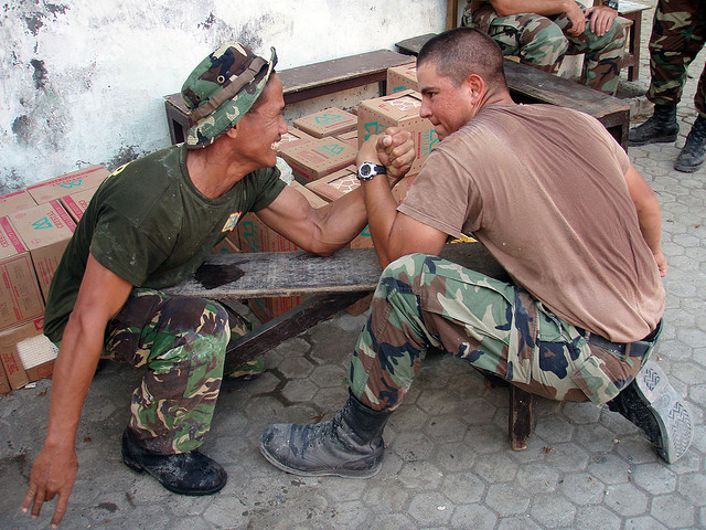 Utilitiesman 3rd Class Orestes Chavez and an Indonesian Marine take a break from placing tile in an Indonesian elementary school to arm wrestle. 