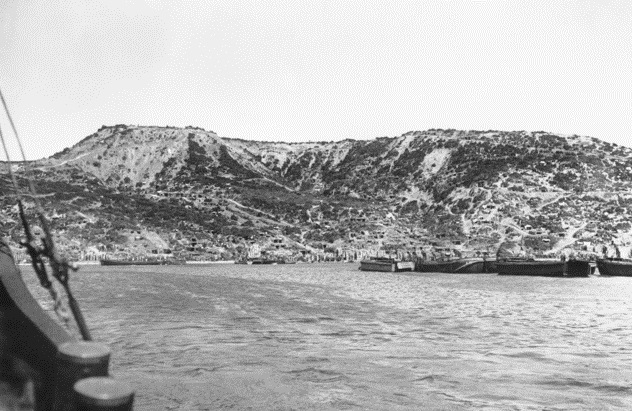 Gallipoli Peninsula, Turkey. Summer 1915. A view from the sea of Anzac Cove. On the left is Ari Burnu, left background is Plugge's Plateau, to the right is MacLagan's Ridge with Anzac Gully between. New Zealand and A Division Headquarters (half-way up hill) are under Plugge's Plateau on the left. This is the left hand image in a two part panorama.