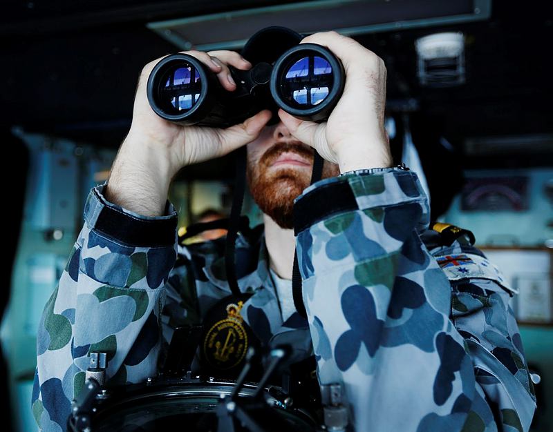 Maritime Warfare Officer, Sub Lieutenant Officer Samuel Archibald searches using binoculars on the bridge of HMAS Perth in the search for missing Malaysian Airlines Flight MH370 as part of OPERATION SOUTHERN INDIAN OCEAN.