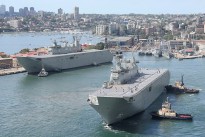 NUSHIP Adelaide is manoeuvred towards her berth at Fleet base East - Garden Island while her sister ship, HMAS Canberra, can be seen near the entrance into the Captain Cook Graving Dock.